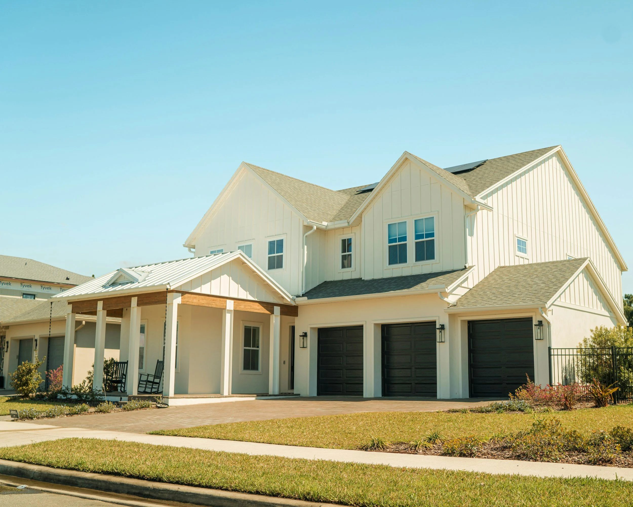 A white two story farmhouse style house with a three car garage in Gwinnett County Georgia