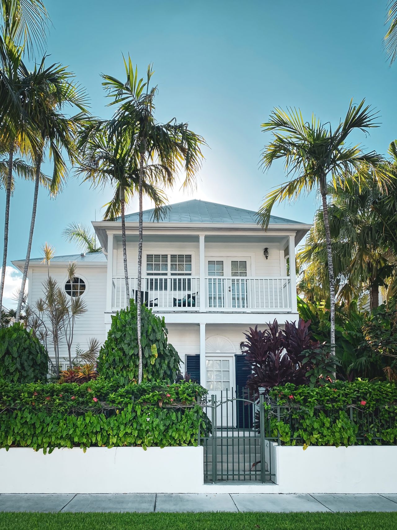 A white two story house with palm trees and a balcony in Miami Florida